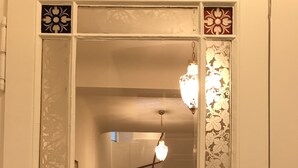 Un couloir agrémenté d’un miroir d écoratif, d’un escalier et d’un luminaire suspendu.