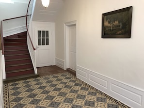 A hallway with a patterned floor, a staircase with a wooden handrail, and a painting on the wall. - Barocker Hof Rhodt (Rhodt unter Rietburg)