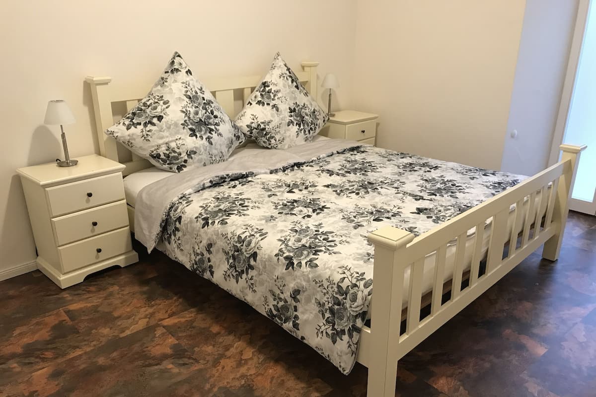 A bedroom with a wooden bed, white nightstands, and a floral bedspread.