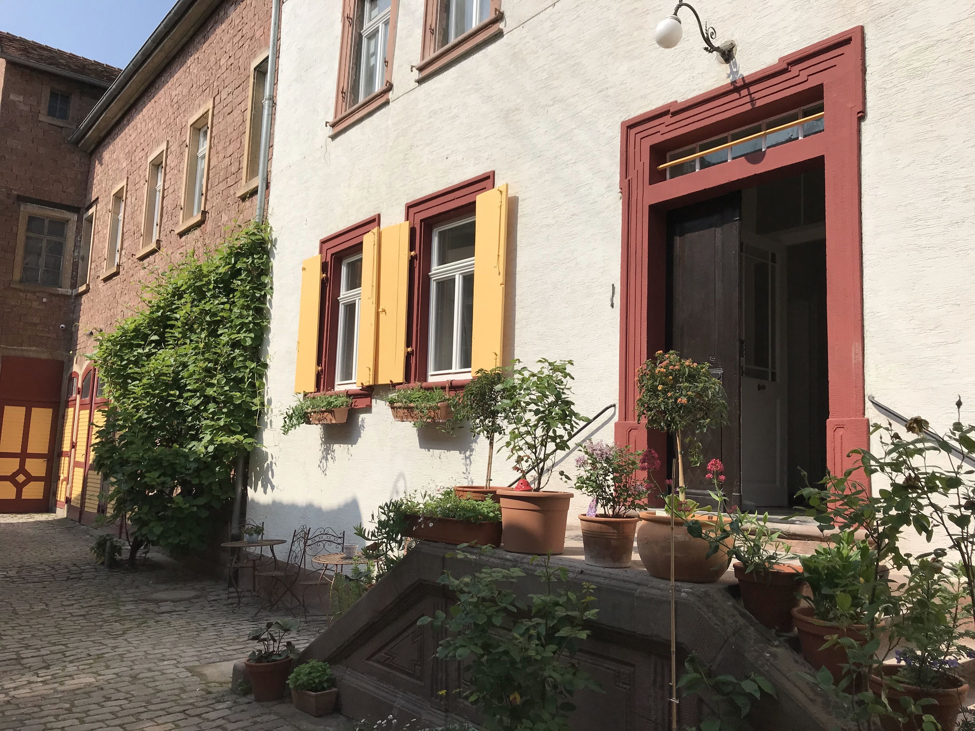 A courtyard with a cobblestone path, potted plants, and outdoor furniture.