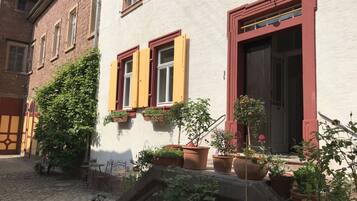 A courtyard with a cobblestone path, potted plants, and outdoor furniture.