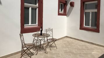 A corner room with two windows, a small table with chairs, and a tiled floor.