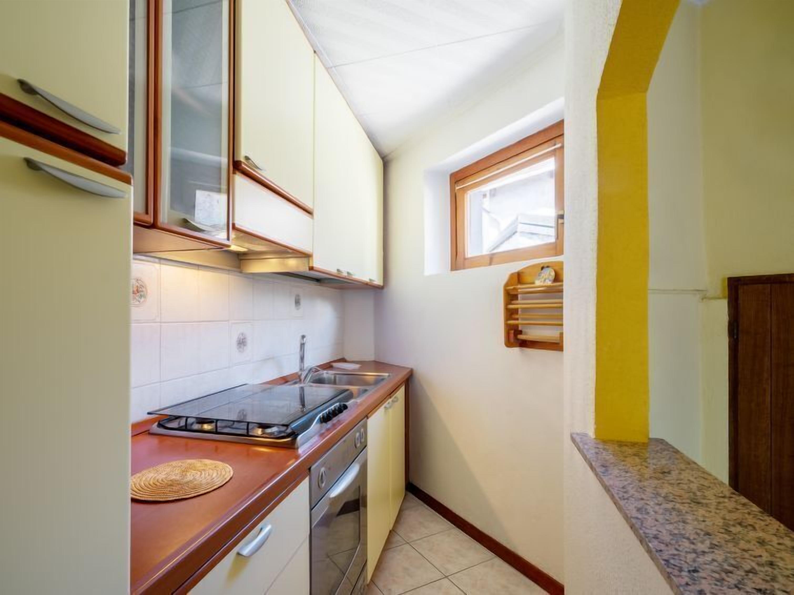 A compact kitchen with white cabinets, a stainless steel sink, and a built-in oven.