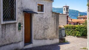 Un vicolo stretto con un edificio che presenta una porta in legno e una finestra con una grata metallica.