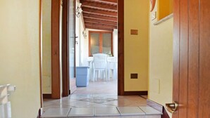 Un corridoio con gradini piastrellati che conducono a una sala da pranzo con sedie bianche e un tavolo.