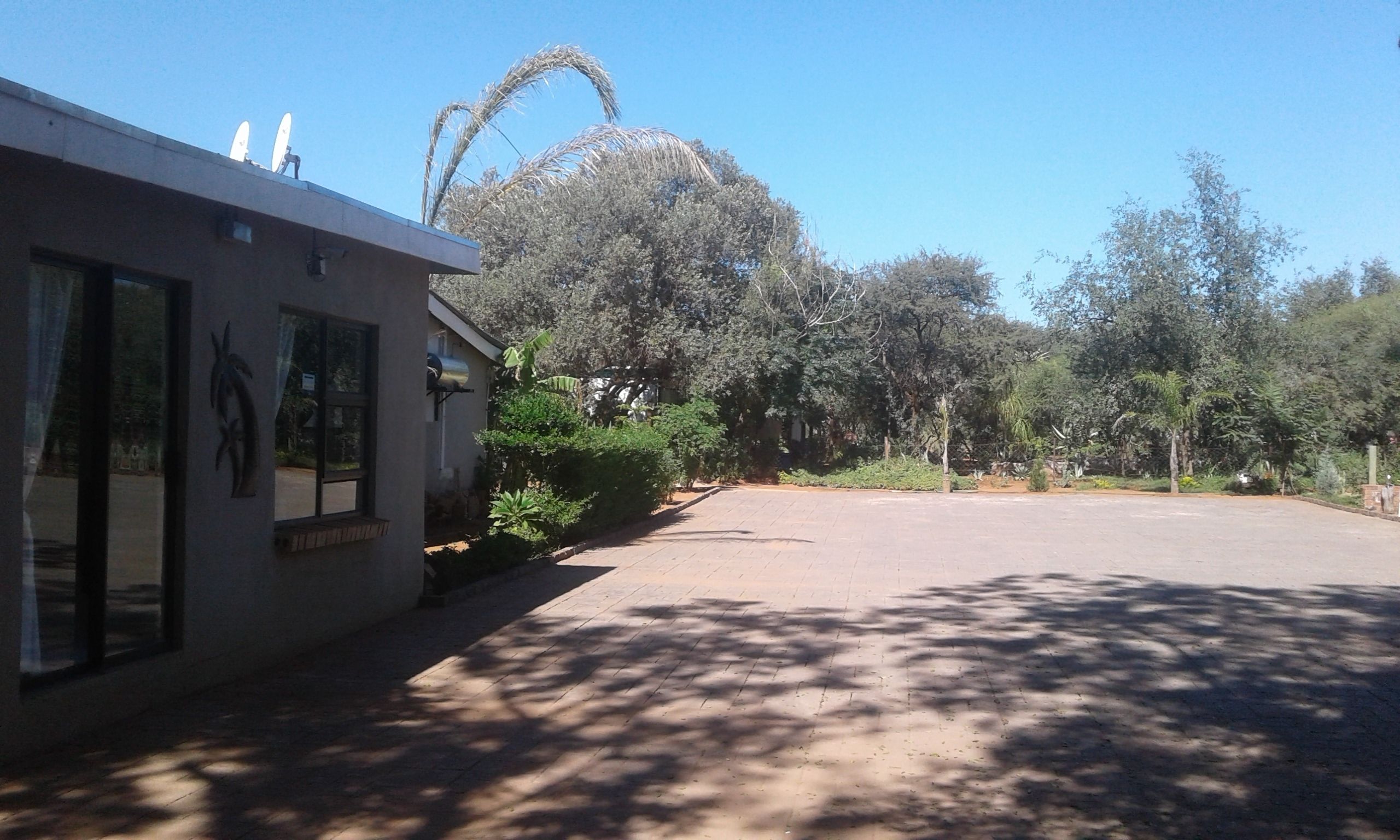 Un bâtiment doté d’une antenne parabolique, d’une allée pavée et entouré d’arbres.
