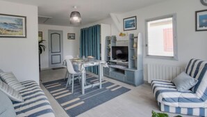 A compact living space with a dining area, a sofa, a TV stand, and a window. - Les Genêts by Interhome (La Richardais)