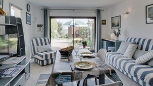 A modern living room with a dining table, striped sofas, and a large window with a view of the outdoors. - Les Genêts by Interhome (La Richardais)