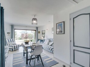 Uma sala de estar moderna com área de jantar, com sofás listrados, uma mesa de jantar e uma grande janela com vista.