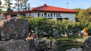 A building with a sign reading "BABAYUL" and a stone pathway leading to it.