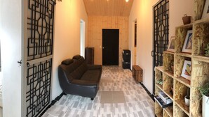 A hallway with a black leather sofa, a wooden bookshelf, and a door at the end.
