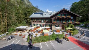 A mountain lodge with outdoor seating, a parking area, and a view of the surrounding forest. - Alpenhaus Kesselfall (Kaprun)