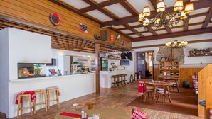 A restaurant with wooden interiors, a bar area, and a fireplace. - Alpenhaus Kesselfall (Kaprun)