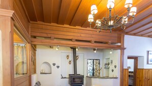 A cozy living room with wooden beams, a fireplace, and white armchairs. - Alpenhaus Kesselfall (Kaprun)