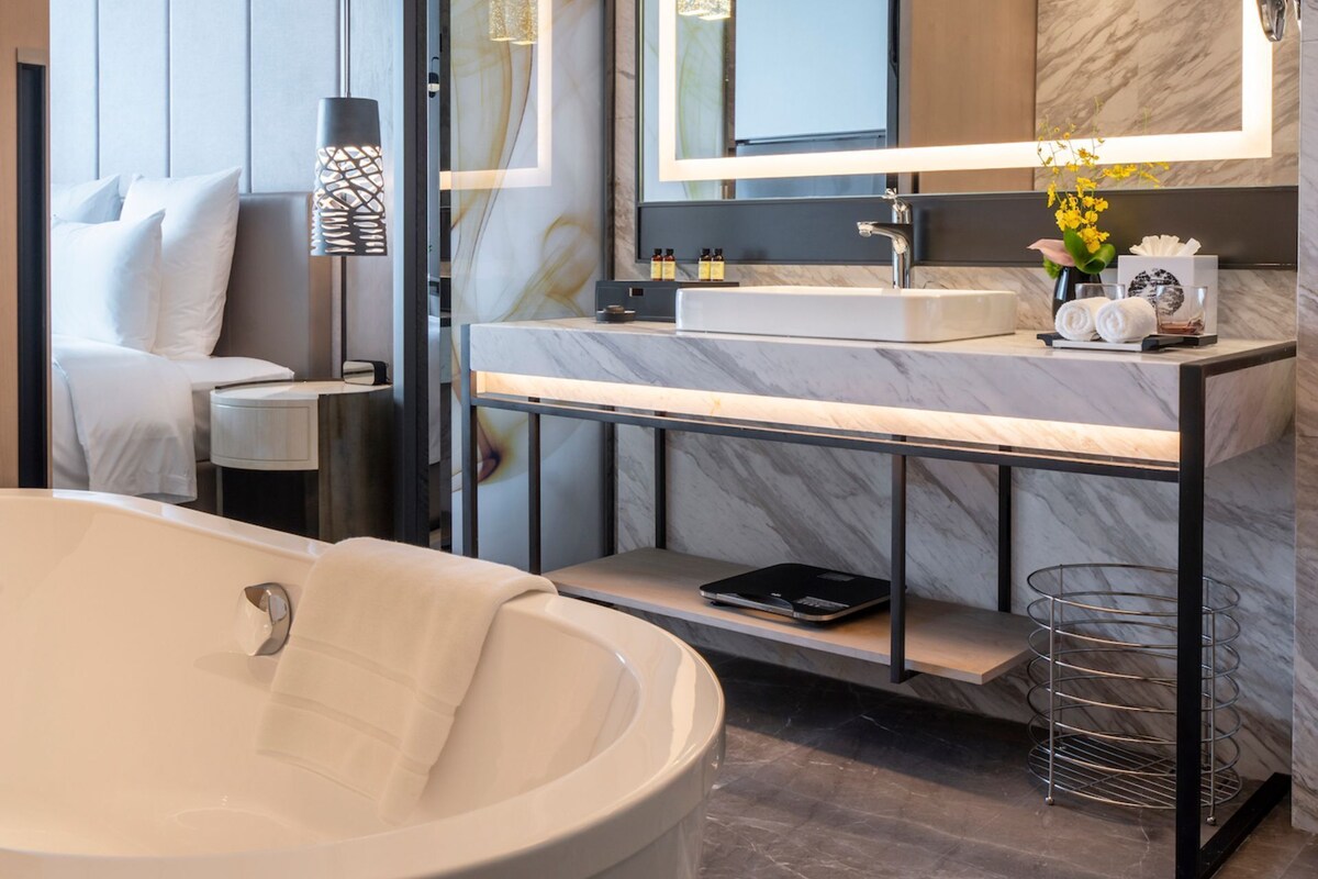 A modern bathroom with a large bathtub, a vanity with a mirror, and a glass-enclosed shower area.