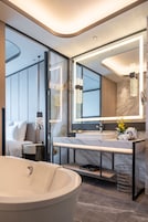 A modern bathroom with a large bathtub, a vanity with a mirror, and a glass-enclosed shower area.