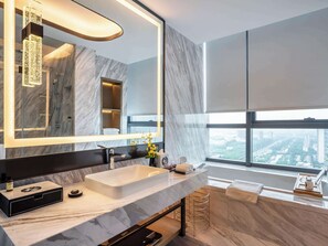 Sink, mirror, and shelf in a bathroom with a city view.