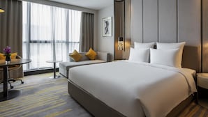 A modern hotel room with a large bed, a desk, and a chair. There is a window with curtains, a painting on the wall, and a lamp. - Pullman Suzhou Zhonghui (Suzhou)