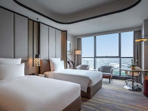 A hotel room with two beds, a desk, a chair, and a large window offering a city view. - Pullman Suzhou Zhonghui (Suzhou)