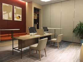 A modern office space with two desks, two chairs, a sofa, and abstract wall art.
