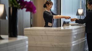 A reception desk with a marble counter, a vase with purple flowers, and a lamp. - Pullman Suzhou Zhonghui (Suzhou)
