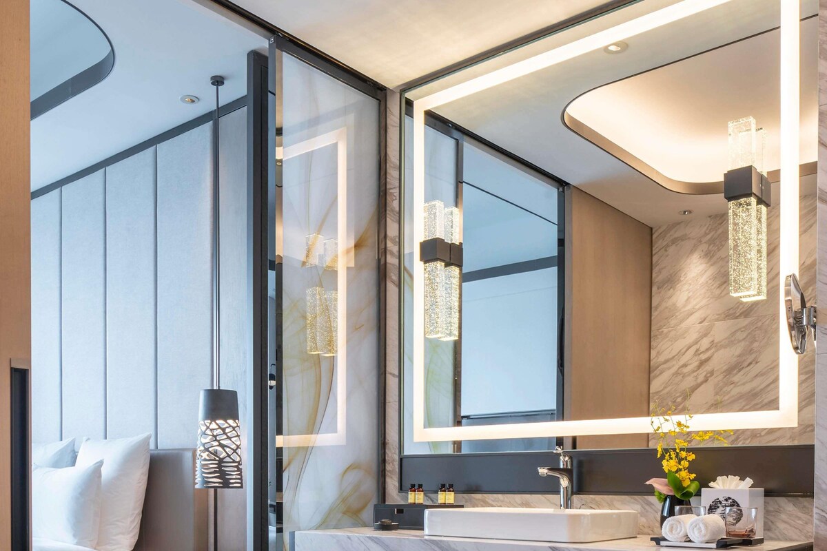 Een moderne badkamer met een grote spiegel, een marmeren aanrechtblad en hanglampen.