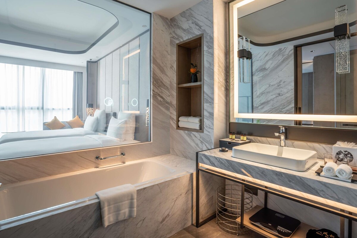 Een moderne badkamer met een grote spiegel, een badkuip, een wastafelmeubel met een wastafel en een douchegedeelte.