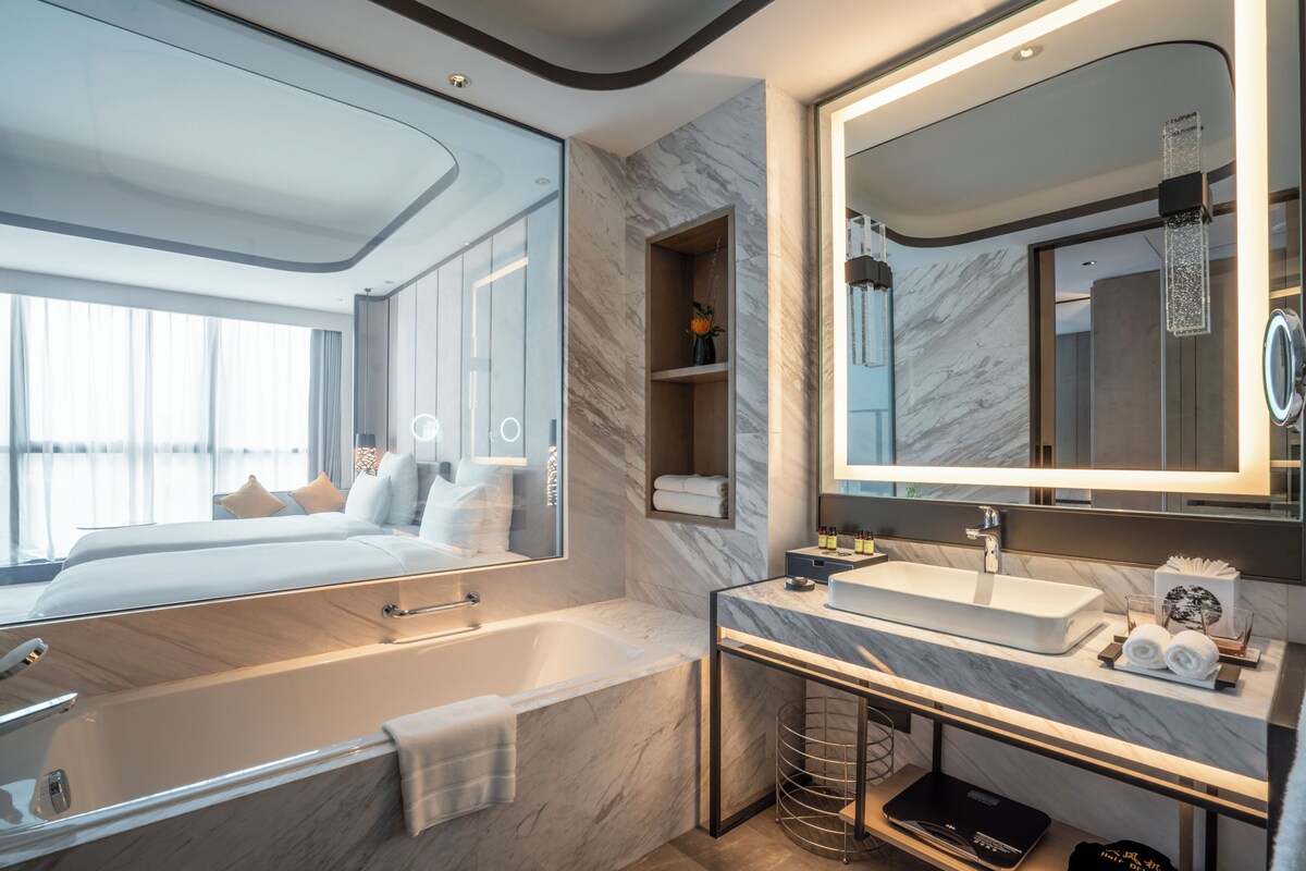 A modern bathroom with a large mirror, a bathtub, a vanity with a sink, and a shower area.