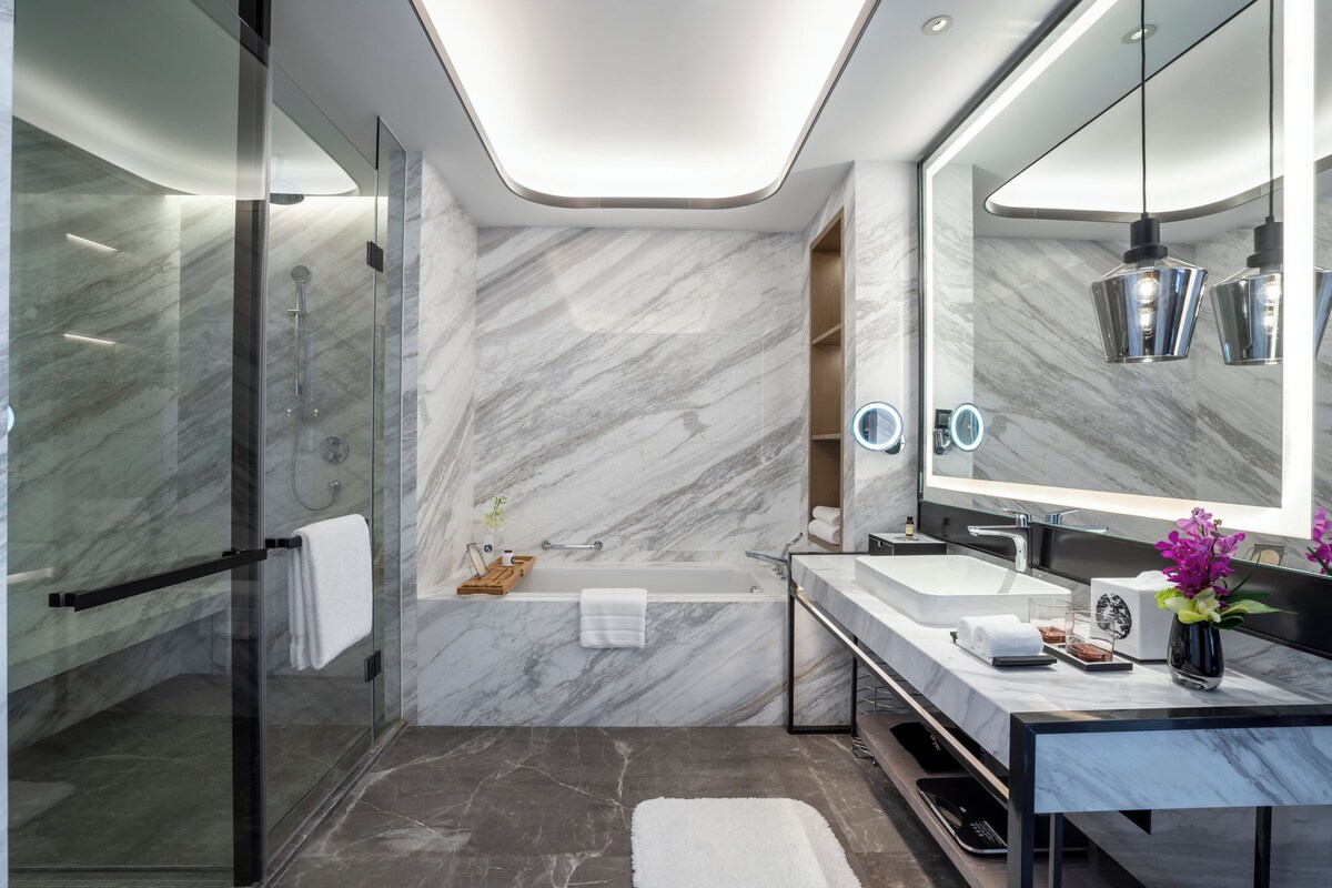 A modern bathroom with a glass-enclosed shower, a freestanding bathtub, and a vanity with a large mirror.