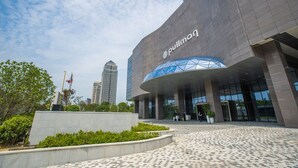 A modern building with the name 'pulmon' prominently displayed, featuring a curved glass entrance and a plaza with a patterned floor. - Pullman Suzhou Zhonghui (Suzhou)