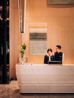 A reception desk with a marble top, a reception sign, and a vase with flowers.