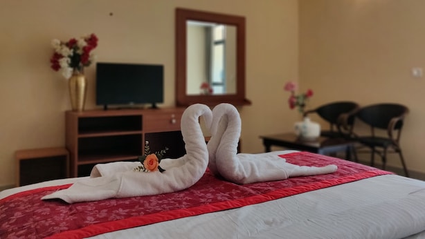 A hotel room with a bed, a television, a desk, and a chair. - Paradise Wild Hills (Hosanagara)