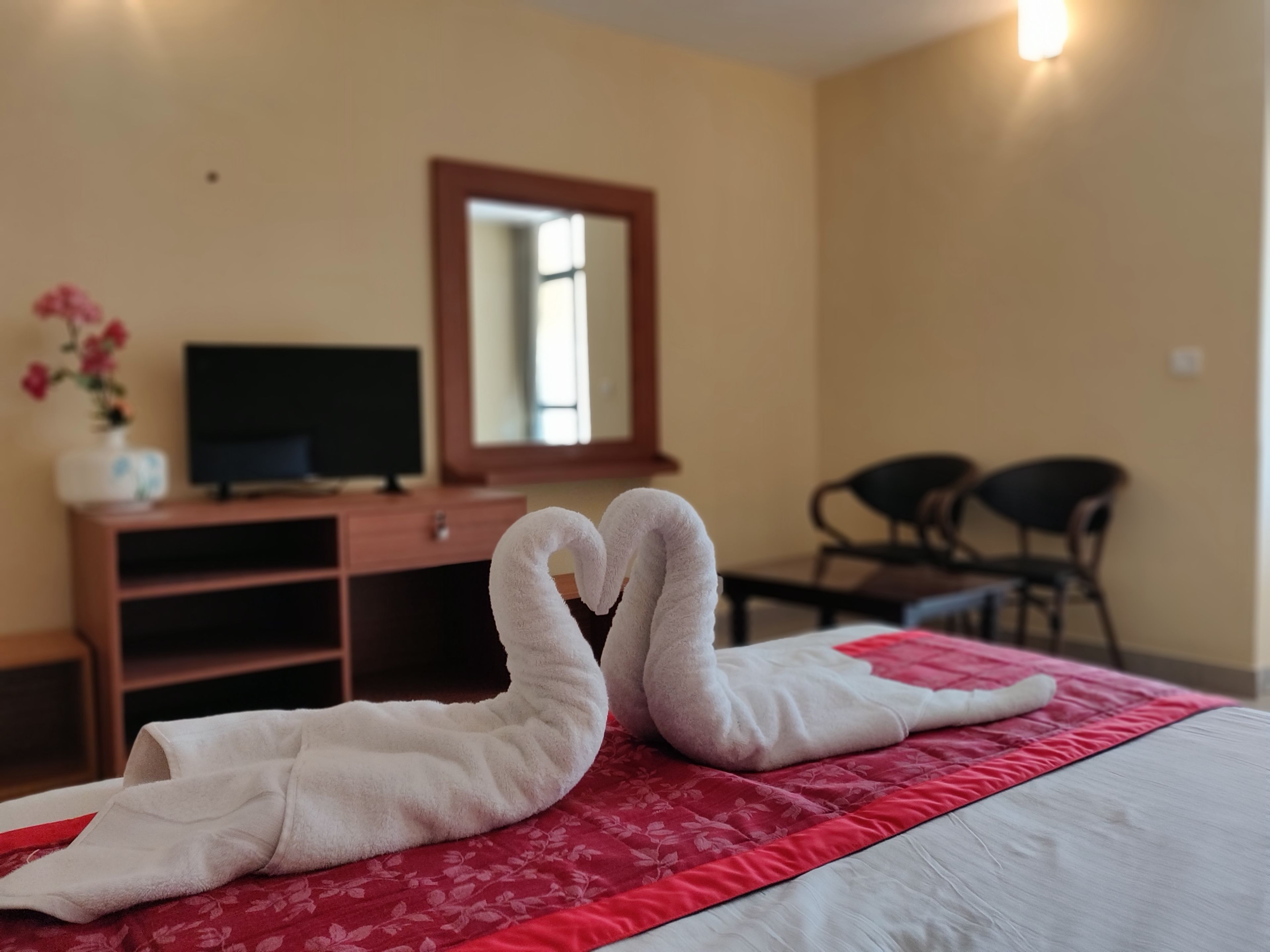 A hotel room with a bed, a TV, a desk, and a chair.