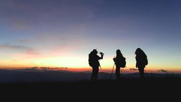 Two people silhouetted against a sunset with a mountainous backdrop.