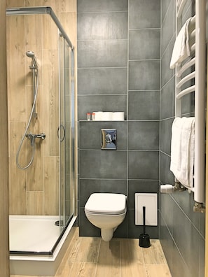 A modern bathroom with a glass-enclosed shower, a toilet, and a towel rack. - Bob Apartments (Kraków)