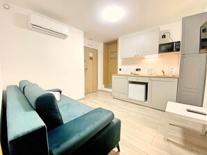 A compact living space with a sofa, kitchenette, and a door leading to another room. - Bob Apartments (Kraków)