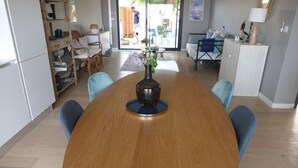 A dining area with a wooden table, chairs, and a vase with flowers. - Villa bottom T3 300 meters from the beach (Arcachon)