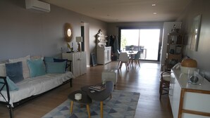 A modern living room with a sofa, coffee table, and dining area. - Villa bottom T3 300 meters from the beach (Arcachon)
