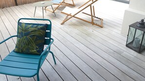 A wooden deck with two lounge chairs, one with a cushion, and a lantern. - Villa bottom T3 300 meters from the beach (Arcachon)