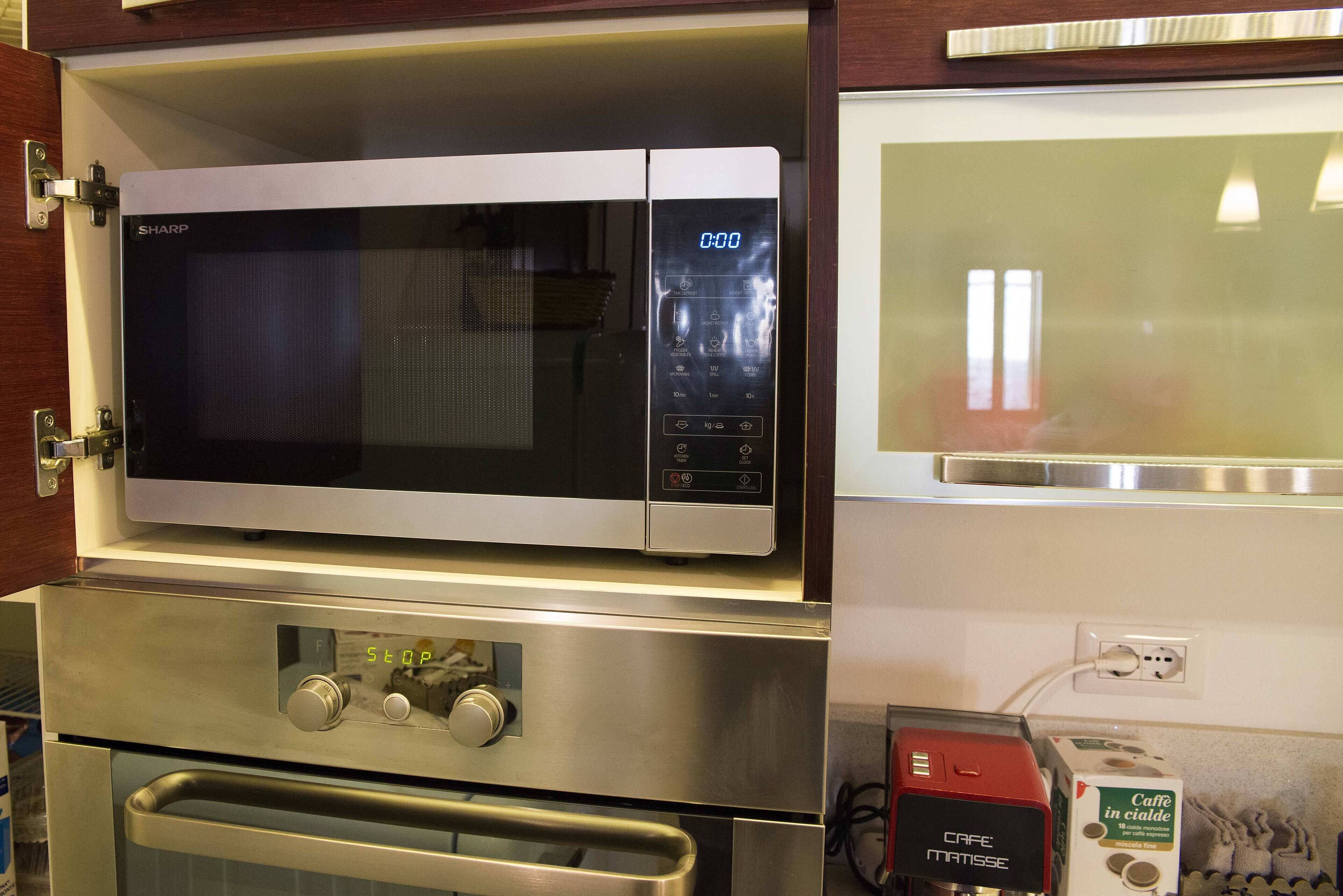 Una cocina con microondas, horno y cafetera.