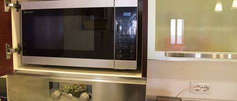 Una cocina con microondas, horno y cafetera.