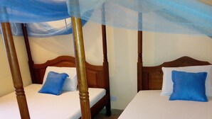 Een kamer met twee houten bedden, elk voorzien van een hemelbed en blauwe kussens.
