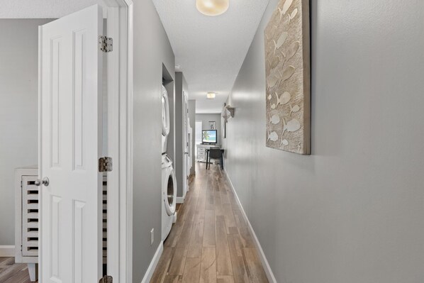A hallway with a washing machine, a door, and a wall-mounted artwork.