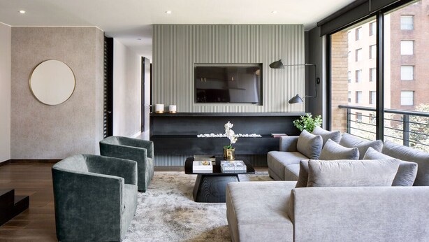 A modern living room with a fireplace, a flat-screen TV, and a large window offering a city view. -  ATTIK SUPERIOR -501 (Bogotá)