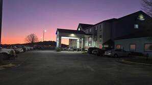 A hotel with a parking lot, a covered entrance, and a building with a Days Inn sign.