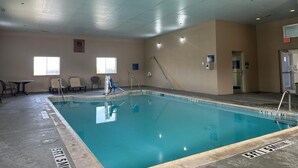 An indoor swimming pool with clear markings, a changing room, and a door leading to an exit.