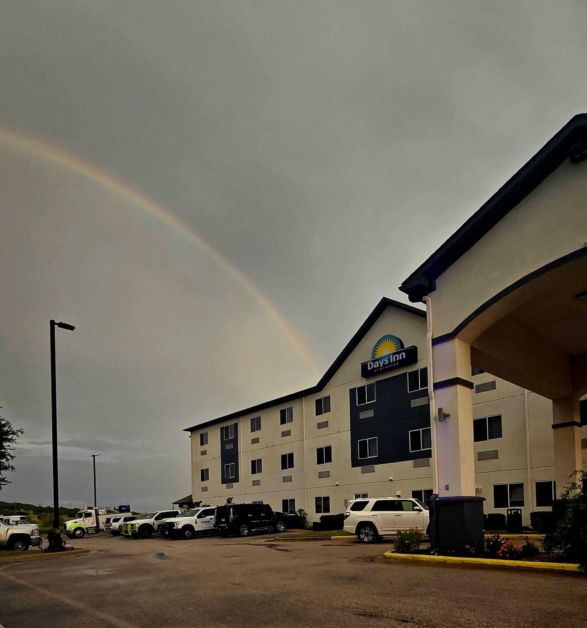 A Days Inn hotel with a large parking lot and a rainbow in the sky.