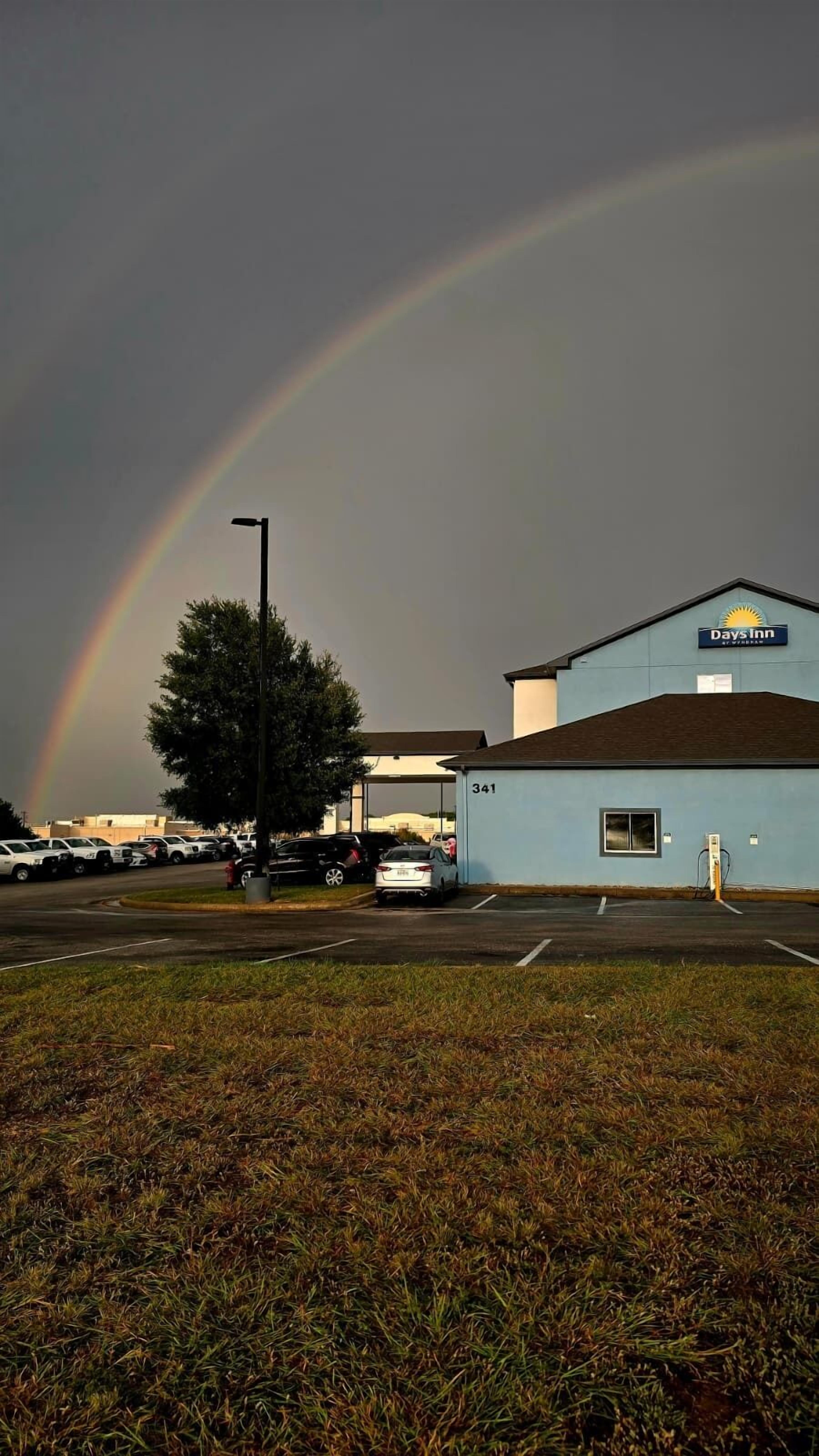 A Days Inn building with a parking lot and a visible rainbow.