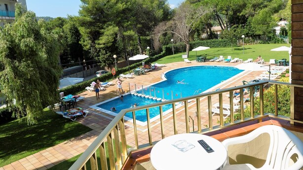 A pool area with a curved pool, lounge chairs, and umbrellas. - APCOSTAS Las Mariposas / One Bedroom (Lloret de mar)