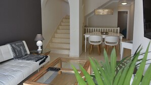 Ein Wohnzimmer mit Sofa, Couchtisch und einer Treppe, die zu einem Essbereich mit Tisch und Stühlen führt.